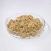 Angled side view of light beige ginseng powder loosely presented in a shallow clear glass dish