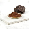 Shilajit powder with dark solid shilajit material behind the dish for nutraceutical ingredient formulation