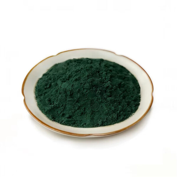 Fine dark green Spirulina powder in a ceramic dish for capsule and tablet supplement manufacturing