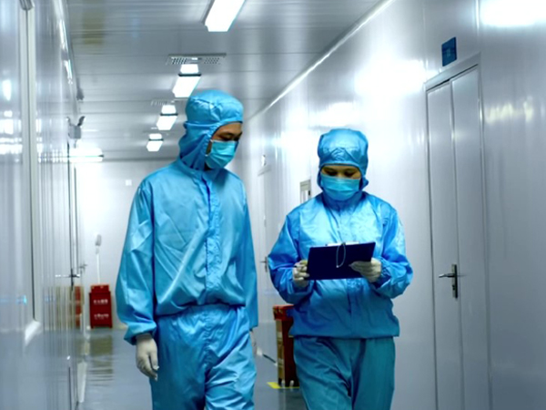 Production staff in protective clothing reviewing documents inside an ingredient manufacturing facility