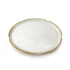 Side-angle view of finely textured white ferulic acid powder forming a gentle mound inside a shallow ceramic dish with a brown rim