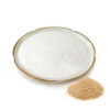 Fine white ferulic acid powder in a ceramic dish beside a separate mound of coarse beige material on a white background