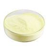 Angled side view of fine, pale yellow genistein powder inside a clear glass dish showing the loose powder surface