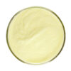 Top view of pale yellow genistein powder spread across a shallow, round glass dish against a white background