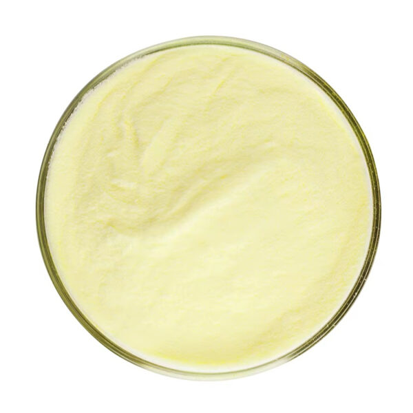 Top view of pale yellow genistein powder spread across a shallow, round glass dish against a white background
