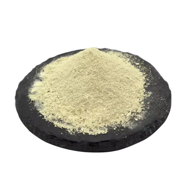 Side view of pale yellow luteolin powder piled into a mound on a dark round slate, showing its fine granular texture
