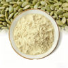 Pumpkin seed extract powder in a shallow white ceramic bowl with green hulled pumpkin seeds across the background