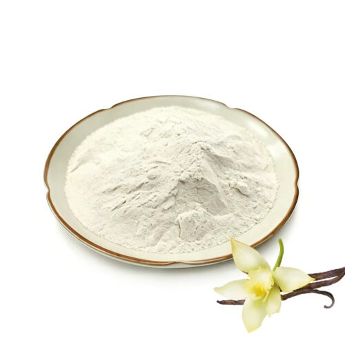 Cream-colored vanilla powder on a shallow plate beside a pale vanilla flower and dark pods on a white background.