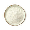 Overhead view of off-white vanilla powder filling a scalloped cream ceramic plate against a white background.